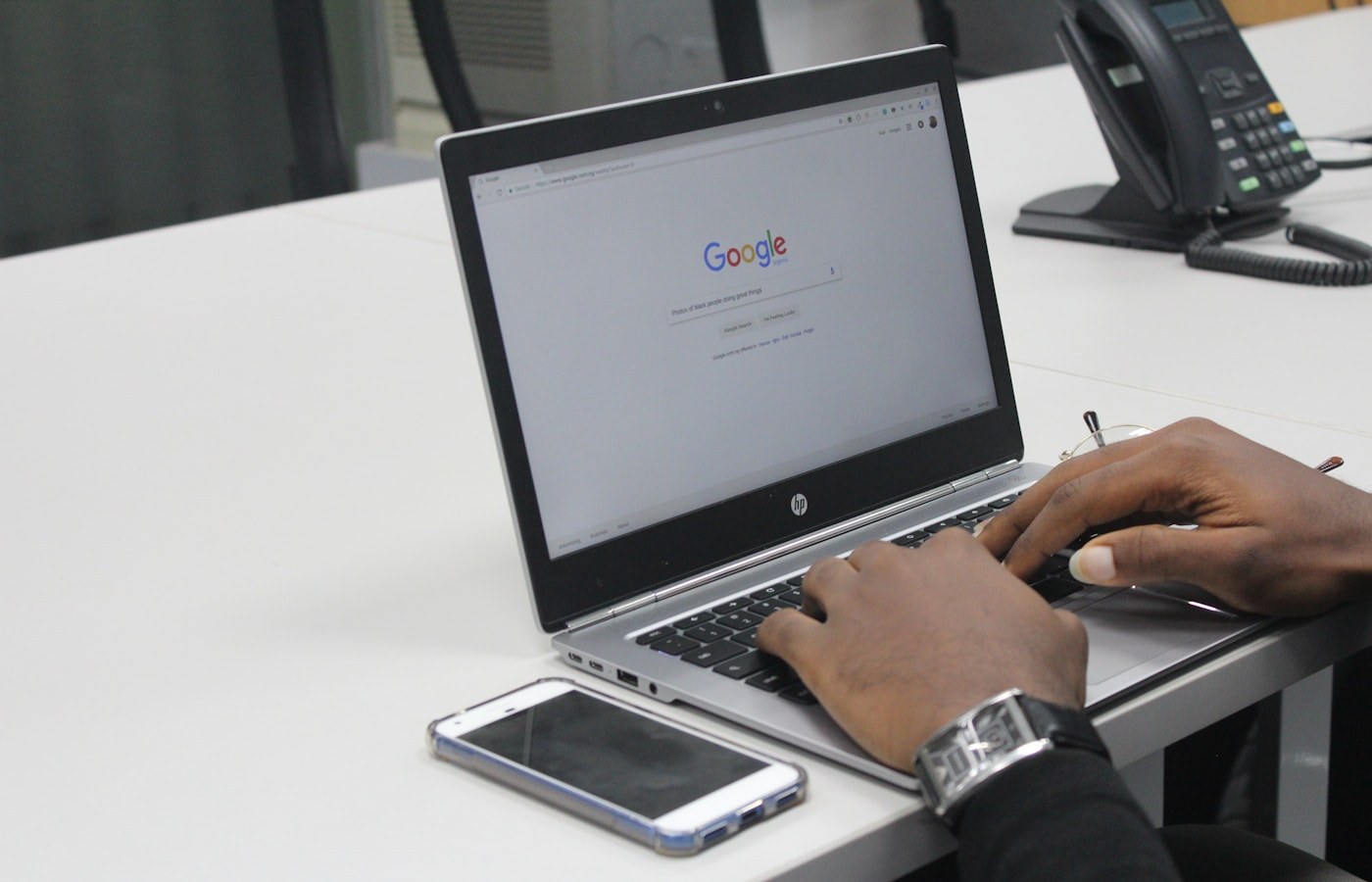 Person searching on Google on a laptop at an office desk