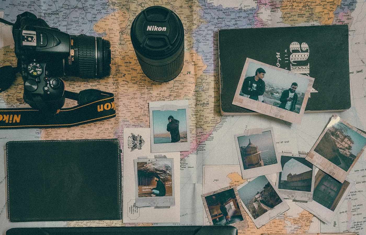 Travel photos, a map and a camera spread across a table while planning a trip