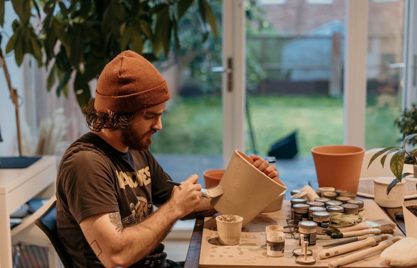 Solo maker painting a handmade pot in a small home studio