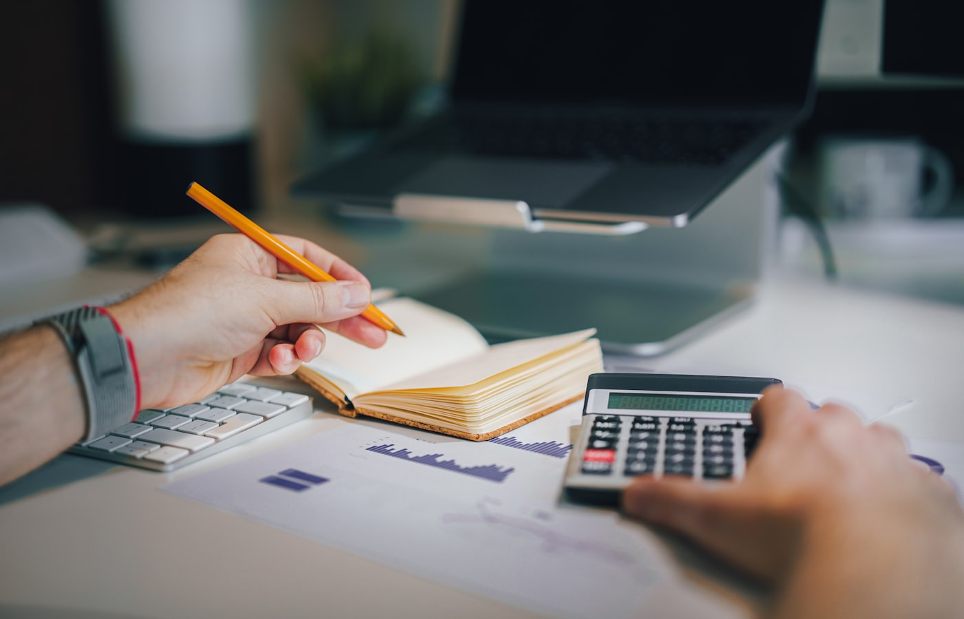Business owner working out the budget for a custom web app with a calculator and notebook