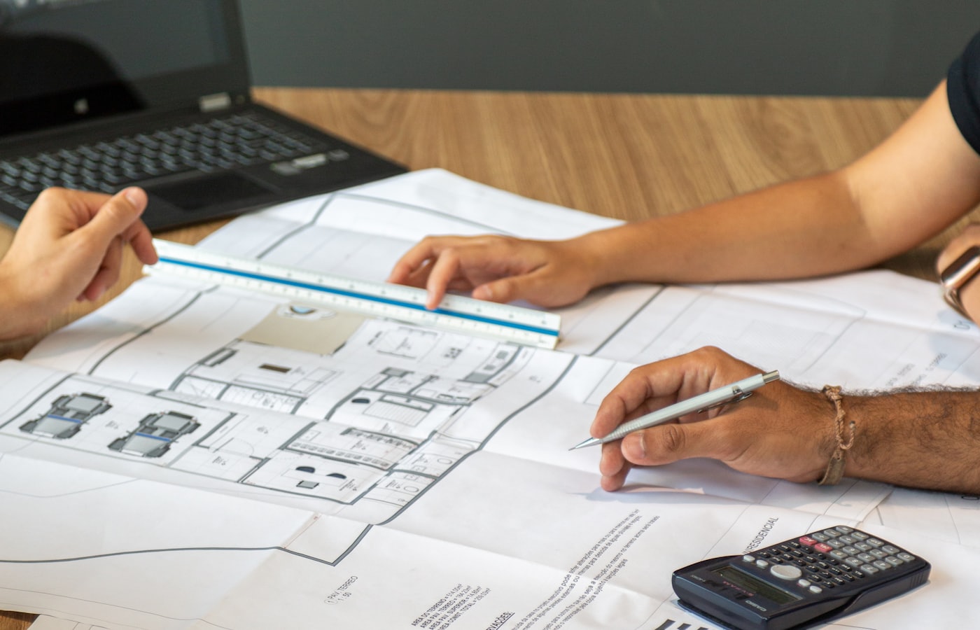 Blueprint and calculator on a desk representing the foundation of a custom web app build