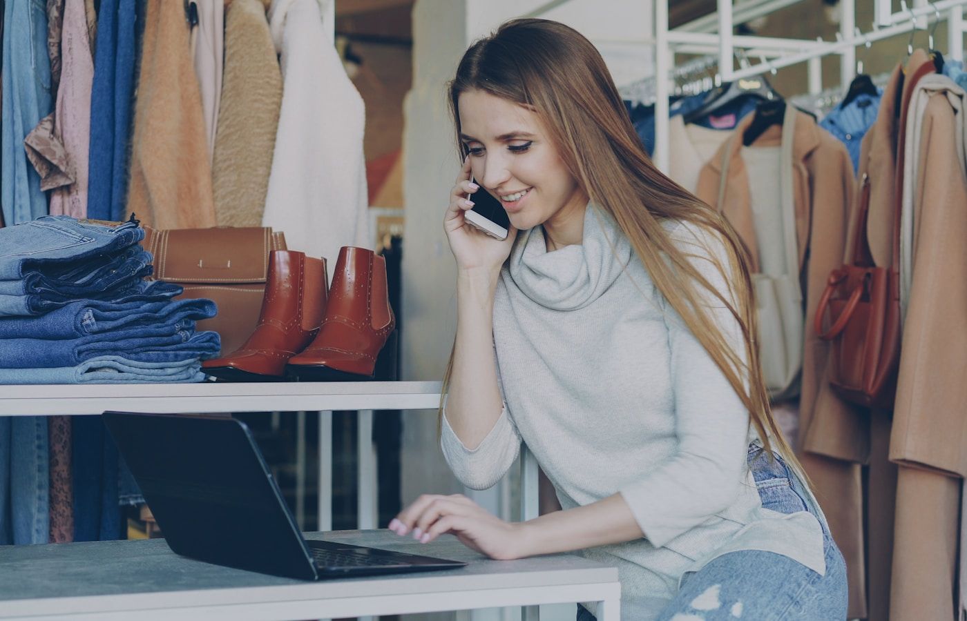 Small business owner on the phone while working at a laptop in her shop