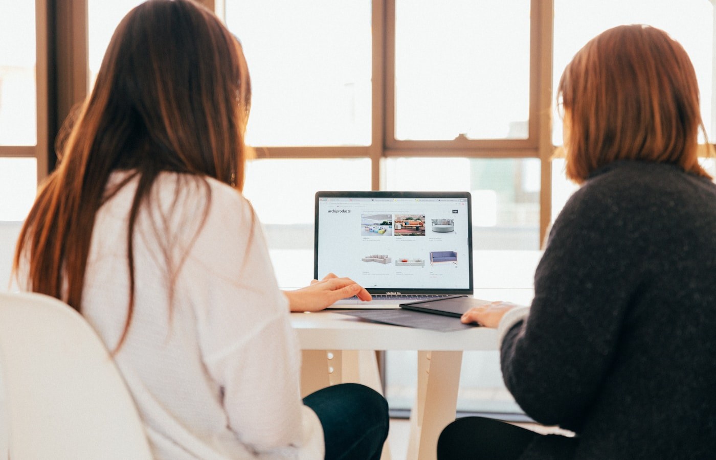 Two people reviewing work together on a laptop partway through a project