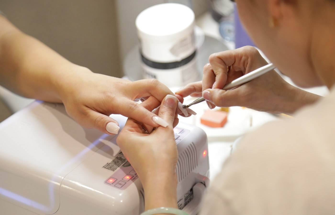 Nail technician carefully working on a client's manicure in a small salon